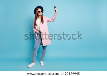 Full size photo of content lovely girl using her cell phone taking selfie wearing pink outfit denim jeans isolated over blue background