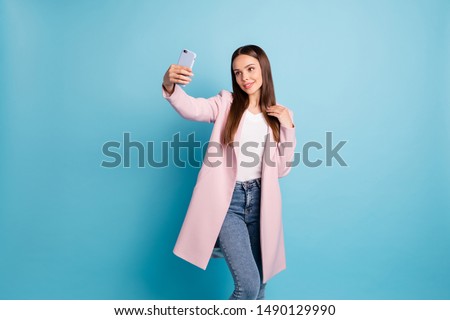Portrait of charming lovely lady using her cellphone making selfie wearing outfit denim jeans isolated over blue background