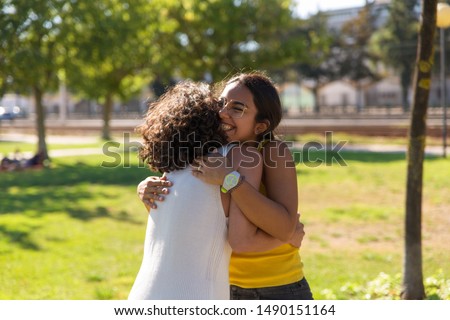 Happy close female friends greeting each other in park. Two women standing outdoors and hugging. Friendship concept Royalty-Free Stock Photo #1490151164