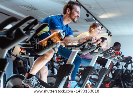 Caucasian man and friends on fitness bike in gym during workout Royalty-Free Stock Photo #1490153018
