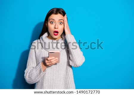 Pretty lady holding telephone hands shocked by news wear warm knitted pullover isolated blue background