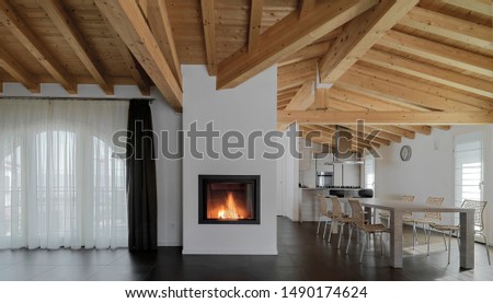 inside view of a modern living room in the foreground the fireplace to its right there's a dining table instead in the background there is the kitchen