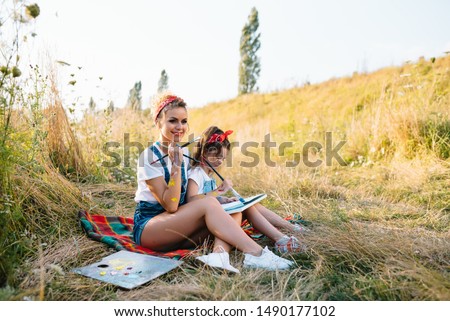Sunny nature, mom and daughter paint a picture in a park , painting a Little Child, Child Creativity. Mother's Day