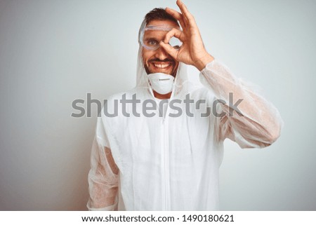 Painter man wearing professional worker equipment protection over isolated background doing ok gesture with hand smiling, eye looking through fingers with happy face.