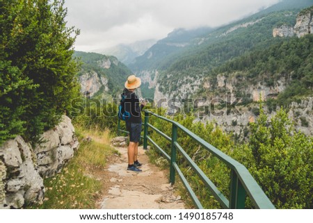 Tourist on the edge of a cliff watching a beautiful view of a valley in the middle of the mountains, Pyrenees, Spain