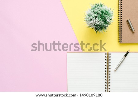 Creative flat lay photo of workspace desk. Top view office desk with open mock up notebooks and pencil and plant on pink yellow pastel color background. Top view with copy space, flat lay photography.
