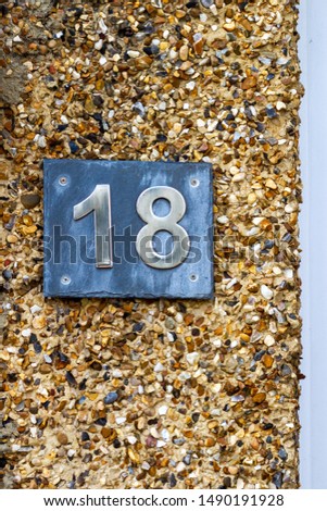 House number 18 on black slate on a structured plaster wall