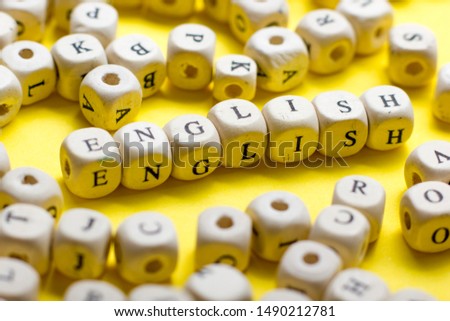 Word english made with block wood letters next to a pile of other letter over wooden table