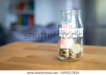 Transparent glass jar labeled travel with euro money in it. Background out of focus. Bokeh.