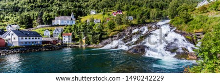 Panorama of small village Hellesylt with Hellesyltfossen waterfall in along Geiranger fjord in More og Romsdal county in Norway