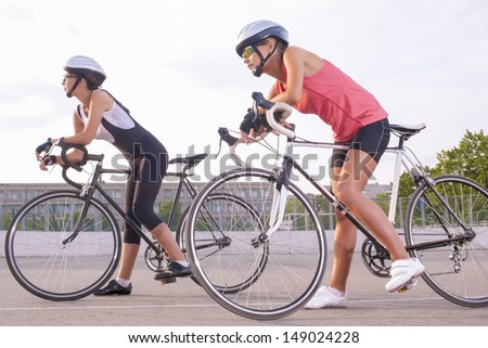 portrait of two young attractive females holding their race bikes and standing on a track. horizontal image