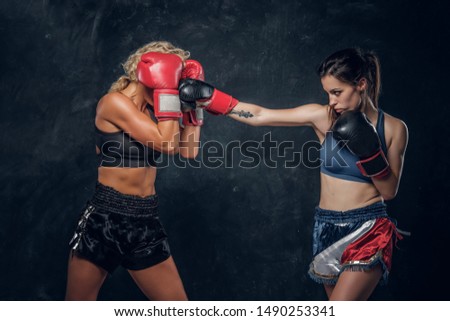 Expirience trainer and her young student have a boxing training wearing boxing gloves.