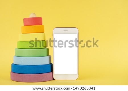Baby multi-colored pyramid and mobile phone mock up on yellow background
