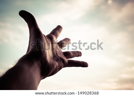 Hand of a man reaching to towards sky. Color toned image.