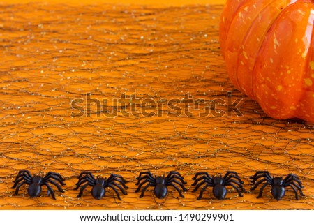 Halloween background. Spiders and pumpkin on an orange background. Traditional halloween attributes. Place for text.