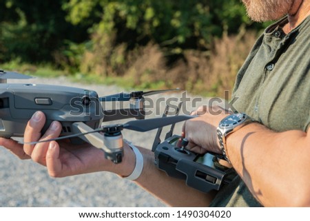 A man in one hand holding a drone, and in the other hand a bullet control of the drone. A fragment of a man's body is depicted. Selective focus. Copy space.