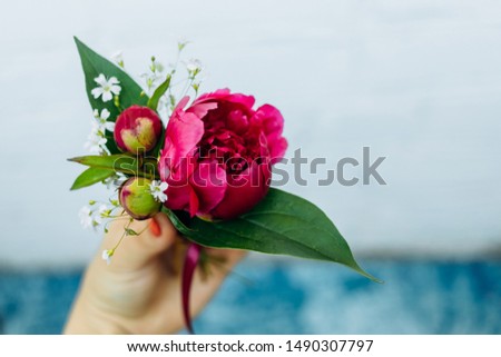 Boutonniere with peonies on a blue background