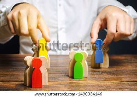 Groups of multicolored wooden people and businessman. The concept of market segmentation. Target audience, customer care. Market group of buyers. Customer relationship management. Selective focus Royalty-Free Stock Photo #1490334146