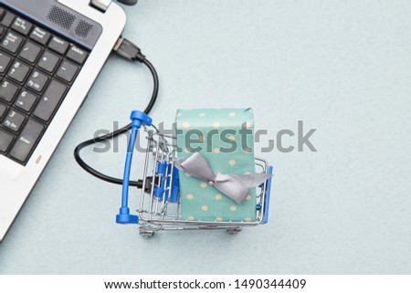 Delivery, online shopping and business concept. Gift lying in the basket and laptop