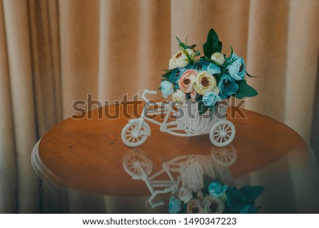artificial flowers in decorative pot in the form of a bicycle. Close-up, shallow depth of field. Picture with reflection