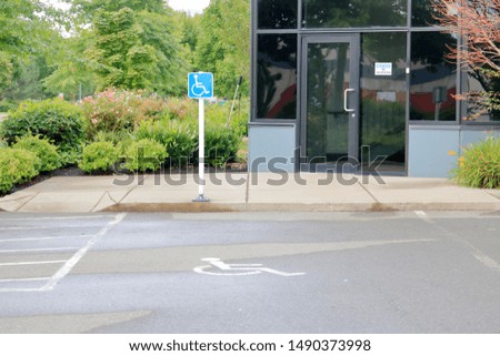 Wide view of an outdoor parking spot clearly identified with logos and signs situated directly in front of a building front entrance. 