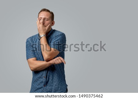 A man with scared face in a shirt shows with his hands on your text or your advertisement on a gray background. Concept banner for advertising, copy space, gray background, commercial design