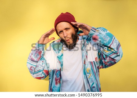 Stylish young hipster man with beard in red hat and a retro jacket of 90s on yellow background.Crazy hipster guy emotions. Collage in magazine style .white blank t-shirt with space for your 
 design.