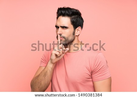 Handsome young man over isolated pink background doing silence gesture