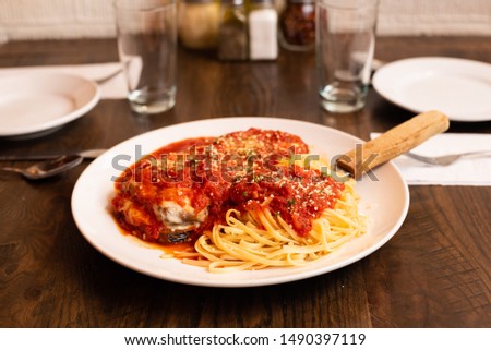 Italian Eggplant Parmesan with Side of Spaghetti and Red Sauce or Red Gravy on a Set Brown Table Royalty-Free Stock Photo #1490397119