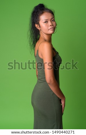 Profile view of young Asian woman with curly hair looking at camera
