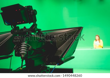 Blur image of newscaster or announcer preparing to record program in broadcast television virtual greenscreen studio room with professional cameras.
