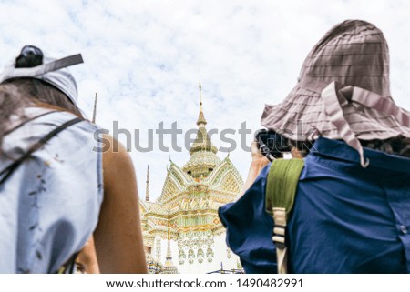Two foreign tourists are taking pictures of the beauty of the pagoda in a temple in Thailand.