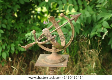 sundial in the garden with green leaves as background