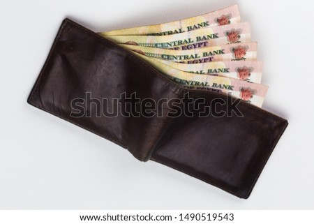 200 Egyptian pound bills in a dark brown wallet isolated on a white background  Royalty-Free Stock Photo #1490519543