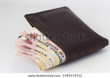 200 Egyptian pound bills in a dark brown wallet isolated on a white background  Royalty-Free Stock Photo #1490519552