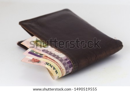 200 Egyptian pound bills in a dark brown wallet isolated on a white background  Royalty-Free Stock Photo #1490519555