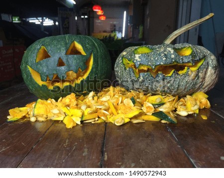The most popular decoration on Halloween is the pumpkin. Halloween pumpkins decorated with pumpkin seeds placed on a wooden table.