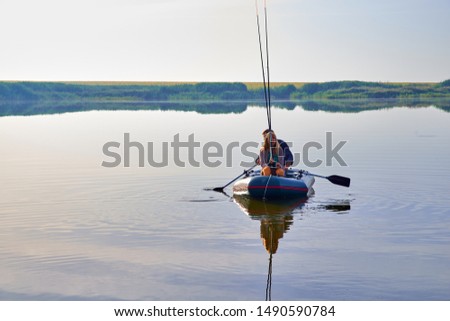 Horizontal picture of a beautiful fishing. An elderly man and woman are fishing in boat around forest and reeds in the evening or early morning.
