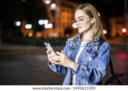 woman using smartphone in city at night