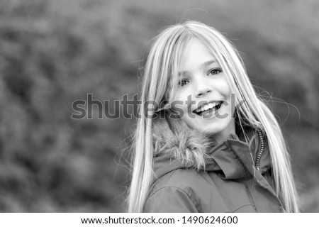 Girl with blond long hair smile on natural environment. Innocence, purity and youth. Beauty, nature, growth. Child in red coat enjoy idyllic autumn day. Happy childhood concept.