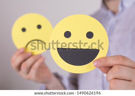 Hand is selecting a happy mood smiley. In front of an empty room