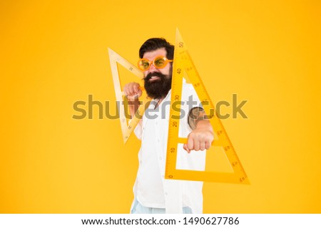 Math genius. Geometry geek holding triangles on yellow background. Geek or nerdy student making angle. Bearded man in fancy geek glasses making technical drawing. Being a geek is extremely liberating.
