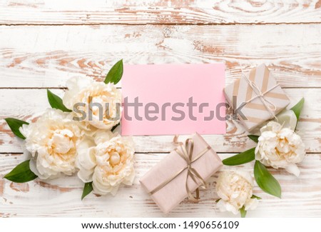 Gift boxes, blank card and beautiful flowers on wooden background