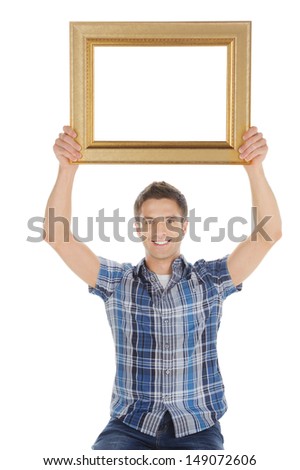 Man with picture frame. Handsome young man holding a picture frame and smiling at camera while isolated on white