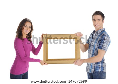 Couple with frame. Beautiful young couple holding a picture frame and smiling at camera while isolated on white