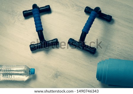 Fitness accessories.  push up bars on wooden background, water bottle, Copy space, toning, vignetting