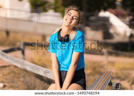 Teenager girl with skate at outdoors smiling