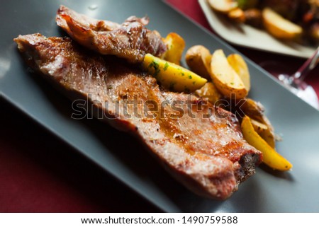 Picture  of delicious fried iberian pork with  fried potatoes at plate on table