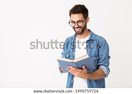 Image of young happy man wearing eyeglasses reading book and smiling isolated over white background Royalty-Free Stock Photo #1490759726