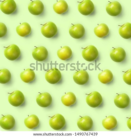 Fresh green apples isolated on green background. Fruits pattern, top view, flat lay